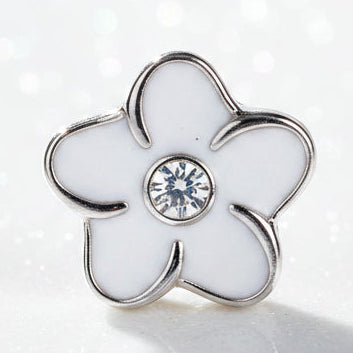 A small white flower-shaped charm or bead with a silver-tone metal outline and a clear rhinestone in the center, locket charm