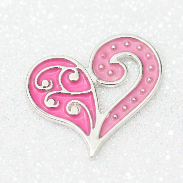 A pink and white decorative heart-shaped charm with swirling filigree details and small rhinestone-like embellishments, shown on a plain white background.