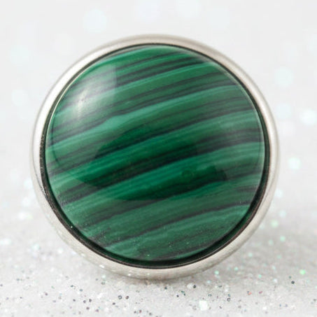 A round sterling silver snap button featuring a polished green malachite stone with natural banding, displayed on a smooth white background.