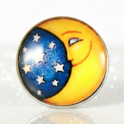 A round snap button featuring a crescent moon and stars design