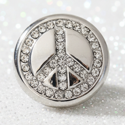A round silver-tone peace sign snap button embellished with clear rhinestones and a light blue enamel center.