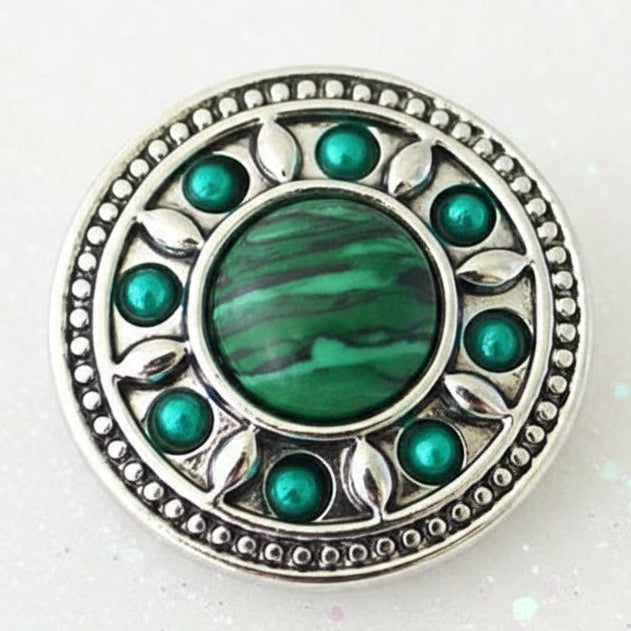 A round silver-toned snap button with a green malachite center and green stone accents, displayed on a smooth white background.