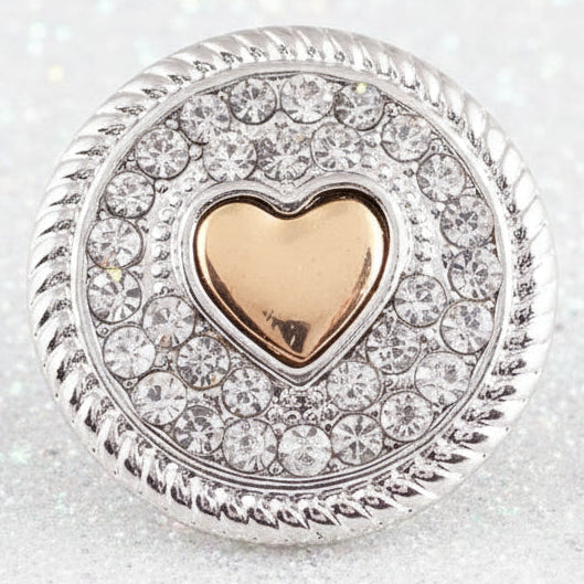A round silver-toned snap button with a central gold heart and surrounding clear pavé stones
