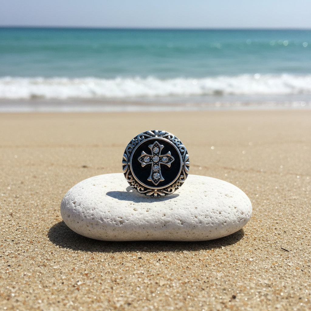 A round gothic-style silver-toned snap button featuring an ornate filigree border and a central black enamel medallion with a silver cross embellished with clear rhinestones.