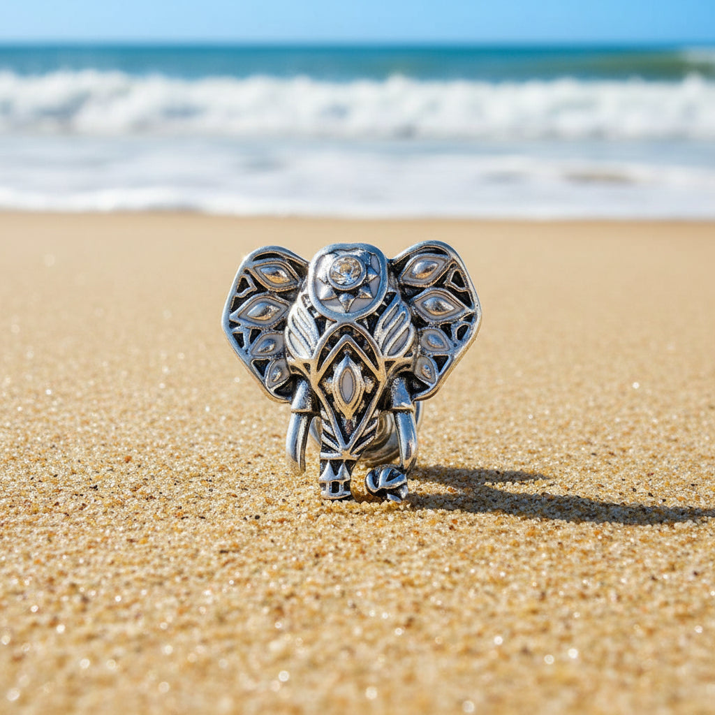 An ornate silver-toned elephant head snap button with intricate filigree detailing and small clear rhinestones, shown on a light textured background.