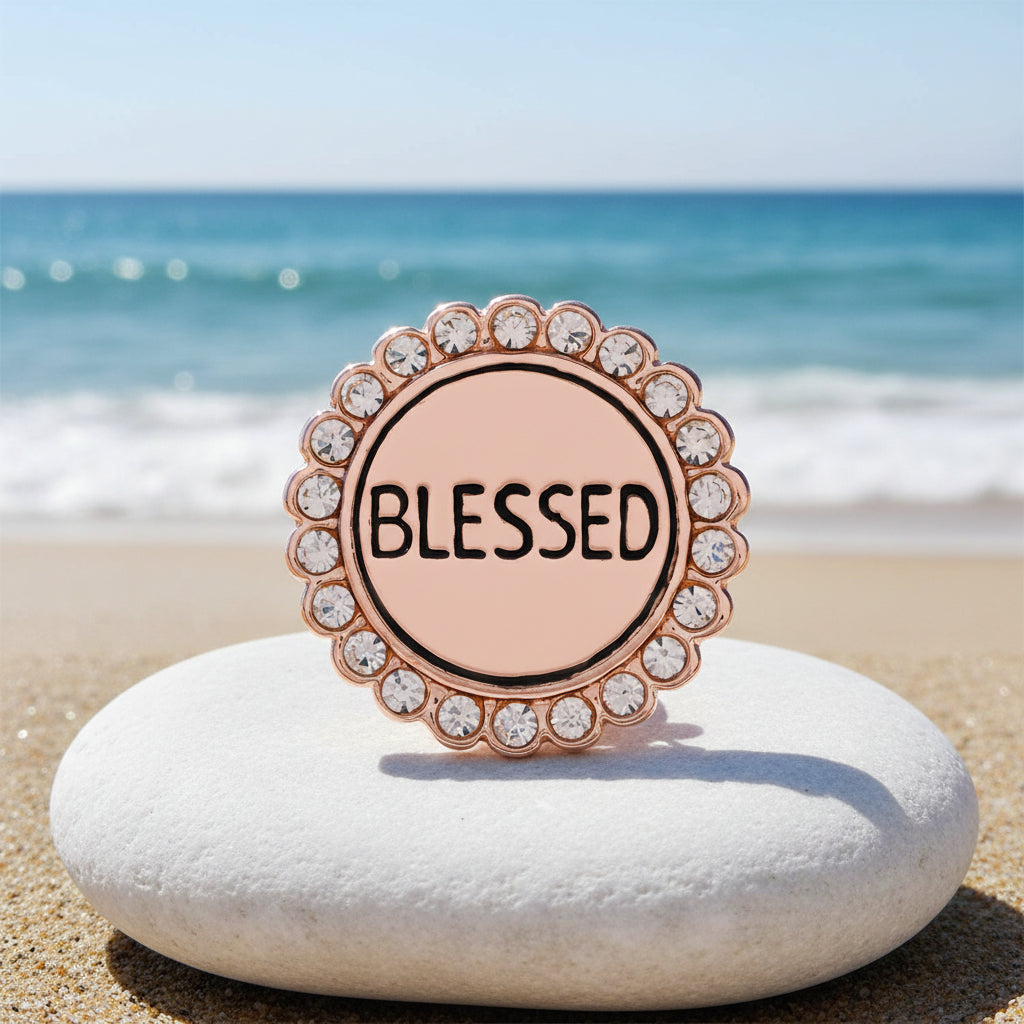 A round rose gold enamel snap button with the word 'BLESSED' in black text, surrounded by a scalloped border of clear rhinestones
