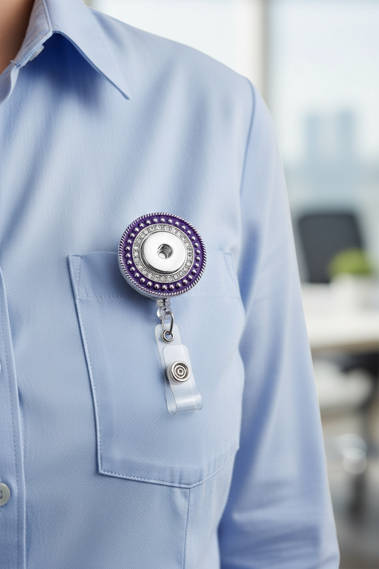 A circular retractable badge reel with a purple and silver design, featuring a clear plastic clip at the bottom.