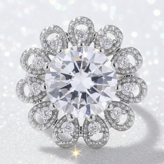 A silver-toned flower-shaped snap button featuring a large round brilliant-cut clear center stone surrounded by multiple smaller clear stones in openwork circular and oval settings, shown on a plain white background.