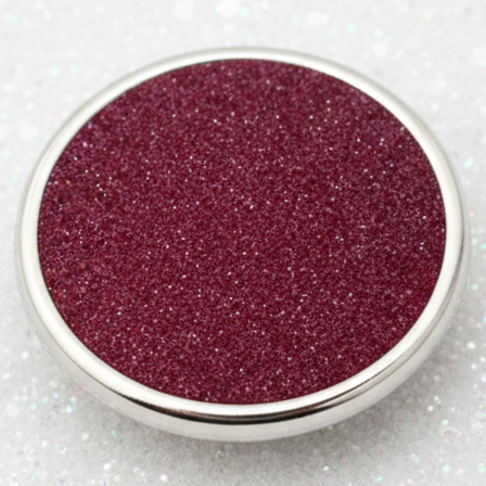 A snap with sparkling deep burgundy glitter, shown from a top-down view on a clean white background.