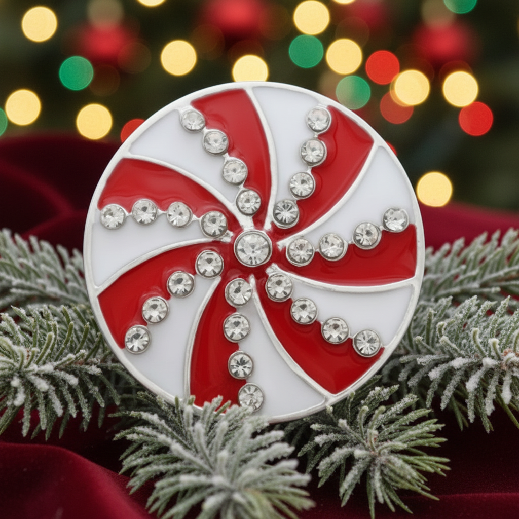 A snap with a red and white swirl pattern, accented with clear rhinestones, shown on a white faux-snow background with a red backdrop and white snowflake decoration.
