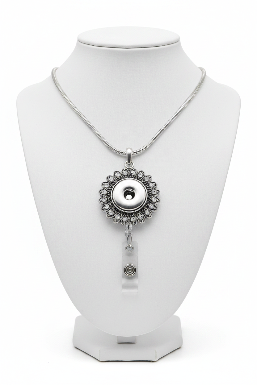 A silver retractable badge reel with a circular floral halo design and a clear plastic clip attached below, shown on a plain white background.