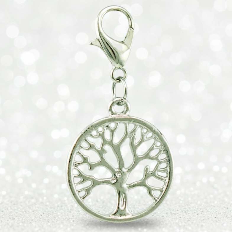 A silver tree of life charm with a circular pendant and lobster clasp, shown against a sparkling white background.