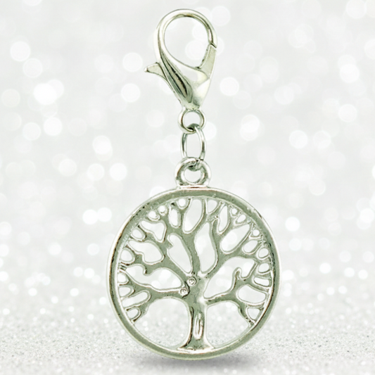 A silver tree of life charm with a circular pendant and lobster clasp, shown against a sparkling white background.