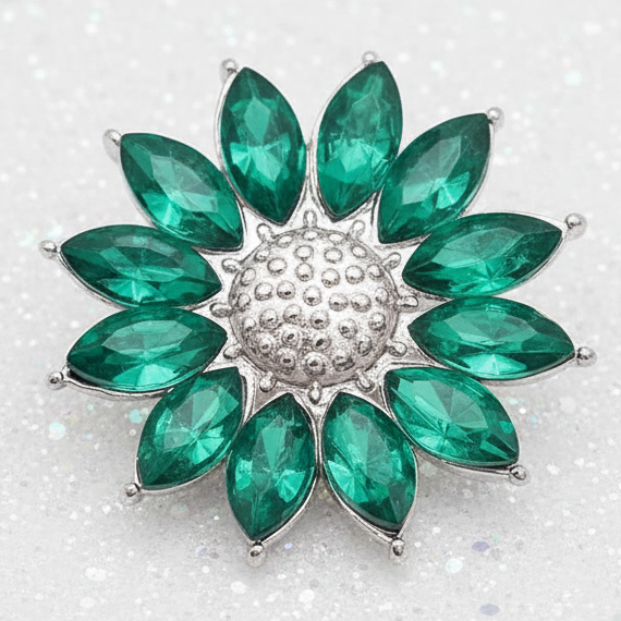 A flower-shaped snap featuring faceted green marquise-cut stones arranged in a circular pattern around a textured silver-toned center, set against a plain white background.