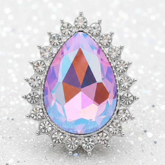 A teardrop-shaped iridescent crystal snap with a silver-toned floral halo setting, displayed on a sparkling white background.