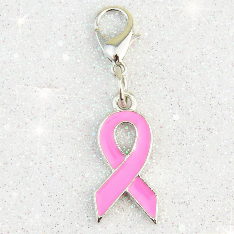 A pink awareness ribbon charm with a silver-tone clasp, shown on a sparkly white background.