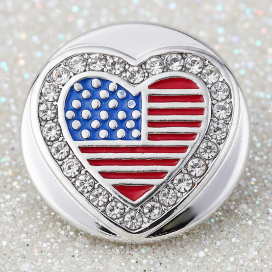 A round silver statement snap featuring a heart-shaped American flag design with a border of clear rhinestones, set against a sparkling silver background.