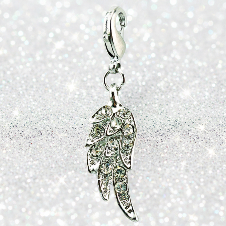 A silver angel wing charm embellished with clear rhinestones, hanging from a silver lobster clasp against a sparkling silver glitter background.